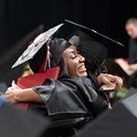 Two girls hugging at a commencement ceremony.